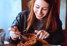 Smiling woman eating meat dish