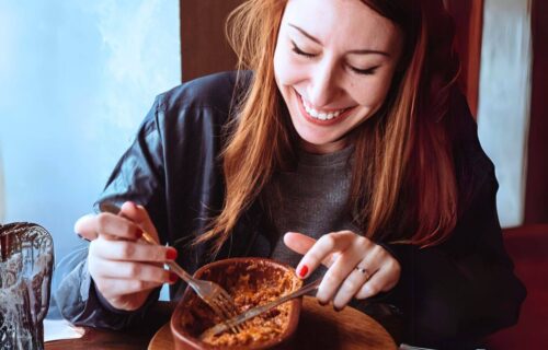 Smiling woman eating meat dish